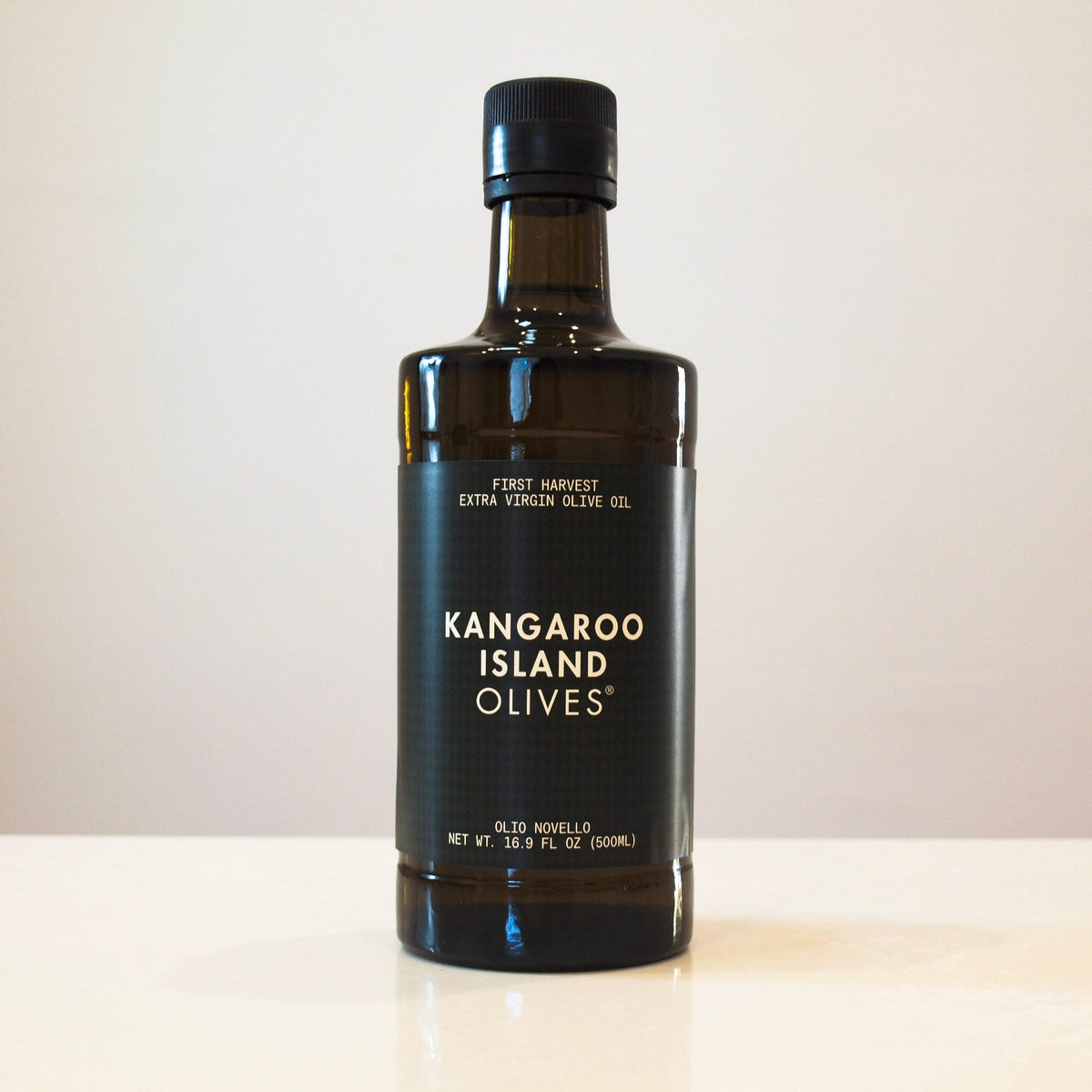 A bottle of Kangaroo Island Olives extra virgin olive oil on a light beige surface against a neutral beige background.