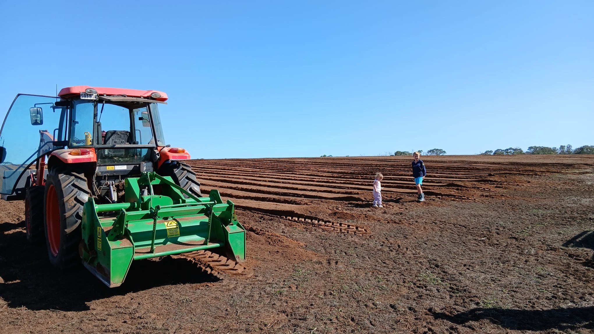 Tractor plowing a field with a clear blue sky
