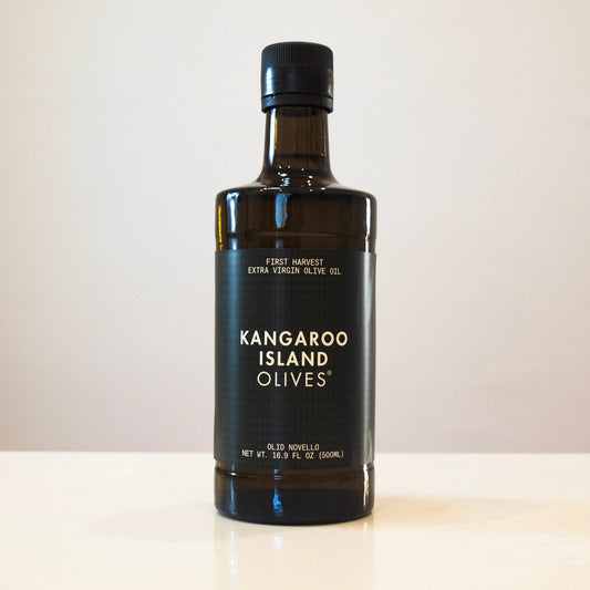 A bottle of Kangaroo Island Olives extra virgin olive oil on a light beige surface against a neutral beige background.